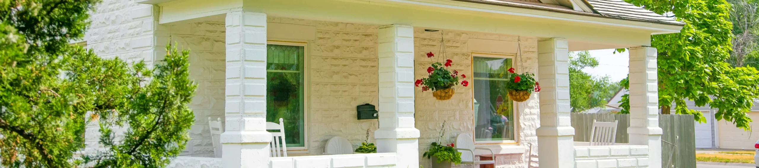 white 2 story house with a white porch and front yard.