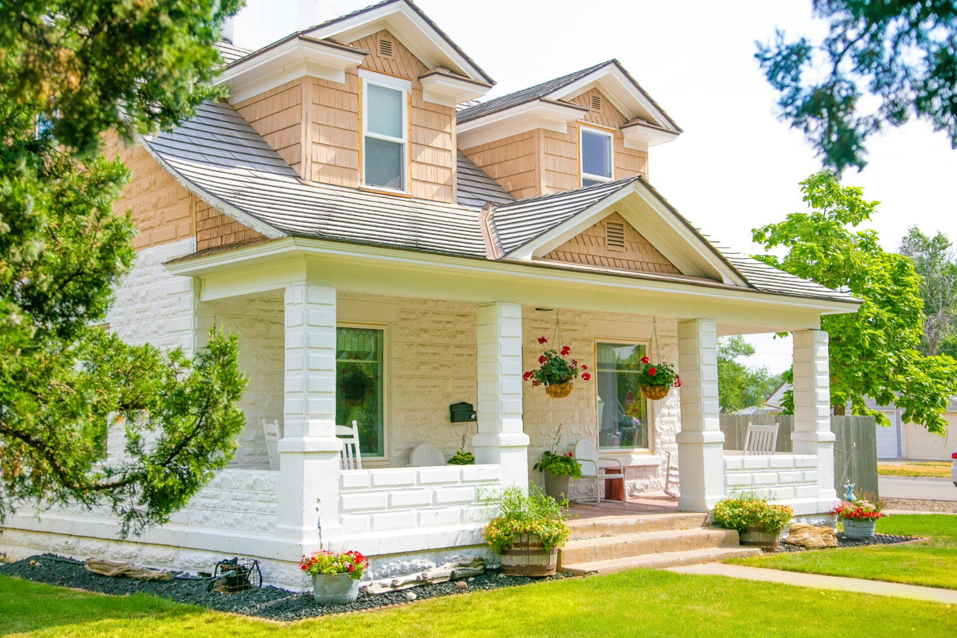 white 2 story house with a white porch and front yard.